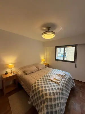 a bedroom with a bed with a blanket and two lamps at Nueva Córdoba Independencia apart in Cordoba