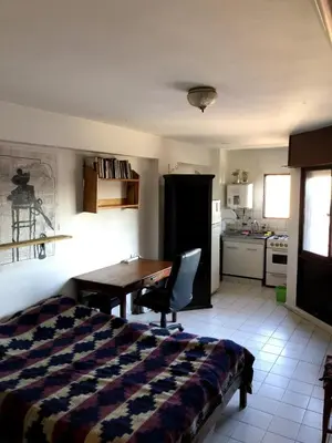 a bedroom with a bed and a desk and a kitchen at Departamento céntrico en Córdoba Capital cerca de todo in Cordoba