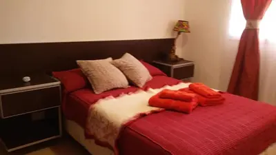 a bedroom with a bed with red sheets and pillows at Mi casa en tanti casa 26 in Tanti