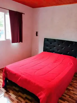 a red bed in a room with a window at Complejo Genesis MALLIN in Cueva de los Pajaritos
