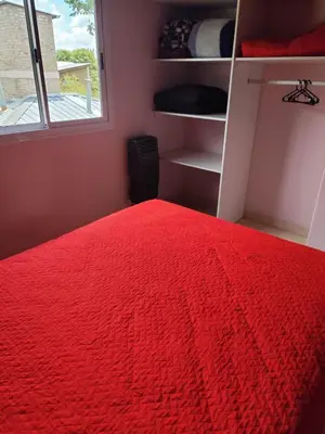 a bedroom with a red bed and a window at Departamentos Pura Fe in Santa Rosa de Calamuchita