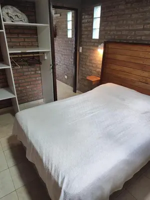 a bedroom with a white bed and a brick wall at Departamentos Pura Fe in Santa Rosa de Calamuchita