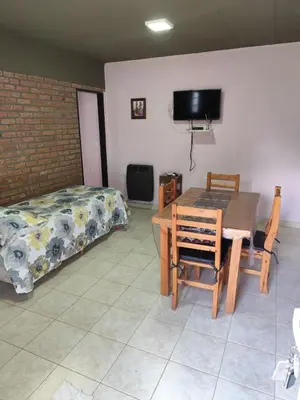 a room with a table and a bed and a table and chairs at Departamentos Pura Fe in Santa Rosa de Calamuchita