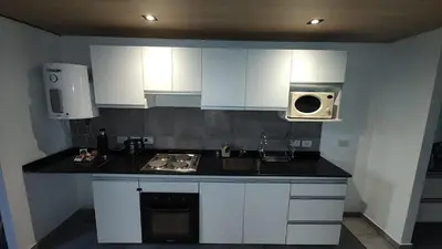 a kitchen with white cabinets and a sink and a microwave at Calixto C in Cordoba