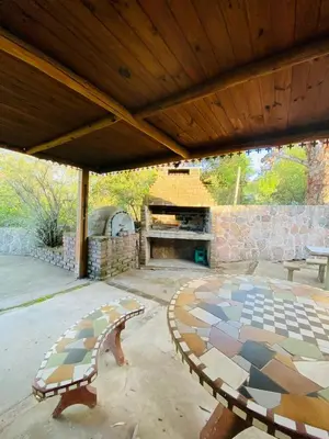 a patio with a table and a stone fireplace at Casa con Piscina y Vista al Lago in Villa Santa Cruz del Lago