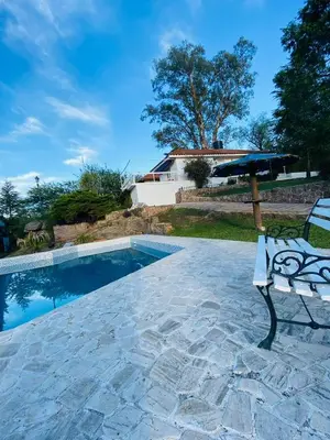 a bench and an umbrella next to a swimming pool at Casa con Piscina y Vista al Lago in Villa Santa Cruz del Lago