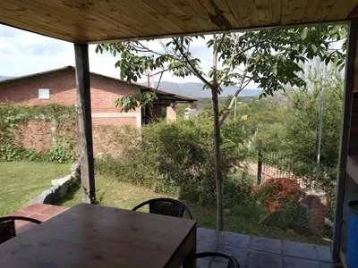 a view from the porch of a house with a table and chairs at Cabañas Quimera in Santa Rosa de Calamuchita