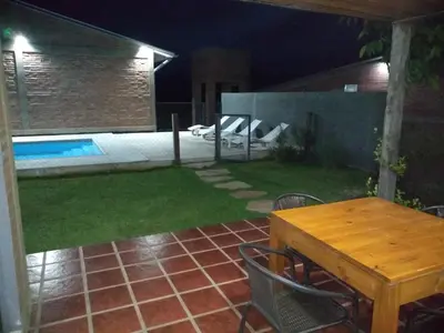 a patio with a table and a pool at night at Cabañas Quimera in Santa Rosa de Calamuchita
