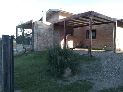 a brick house with a wooden pavilion in a yard at Cabañas Quimera in Santa Rosa de Calamuchita