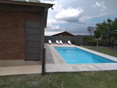 a swimming pool with chairs next to a house at Cabañas Quimera in Santa Rosa de Calamuchita
