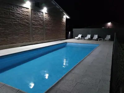 a swimming pool at night with chairs around it at Cabañas Quimera in Santa Rosa de Calamuchita
