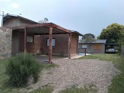 a brick house with a pavilion in the yard at Cabañas Quimera in Santa Rosa de Calamuchita