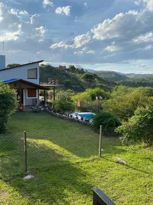a house with a fence and a yard with a pool at Brisas Serranas in Villa Icho Cruz