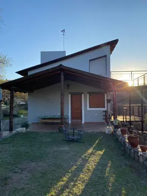 a small white house with a picnic table in the yard at Brisas Serranas in Villa Icho Cruz