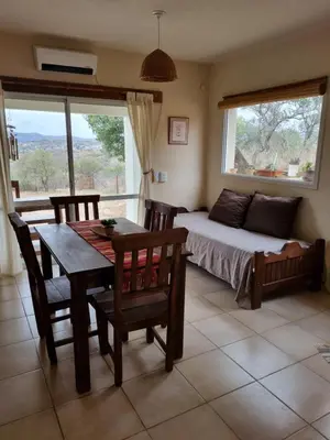 a living room with a table and a bed and a window at Ventura 1 in Villa Carlos Paz