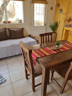 a living room with a wooden table and a bed at Ventura 1 in Villa Carlos Paz