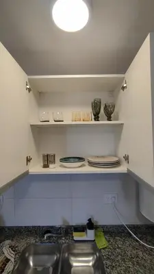 a kitchen with a sink and plates on shelves at Habitana Firpo Cofico con cochera in Cordoba