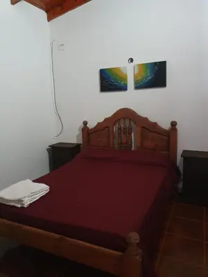 a bedroom with a wooden bed with a red bedspread at Cabañas Sierra Maestra in Bialet Massé