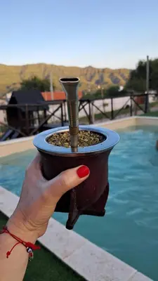 a hand holding a bird feeder next to a pool at Cabañas Sierra Maestra in Bialet Massé