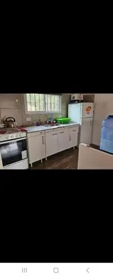 a kitchen with white cabinets and appliances in a room at La Bonita, casa en alquiler frente al lago in La Estancia