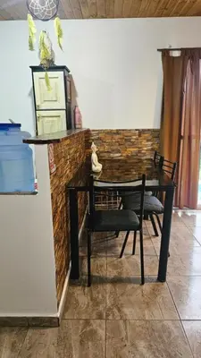 a table and chairs in a room with a brick wall at La Bonita, casa en alquiler frente al lago in La Estancia