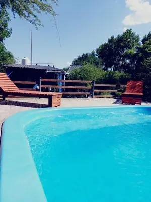 a large pool of blue water next to two benches at Abrazo del Sol in Villa Santa Cruz del Lago