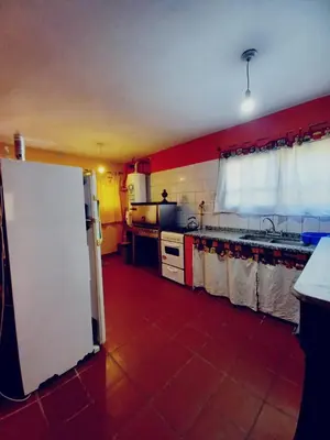 a kitchen with a white refrigerator and a red tile floor at Abrazo del Sol in Villa Santa Cruz del Lago