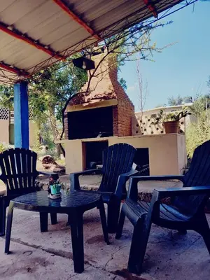 a patio with two chairs and a table and a fireplace at Abrazo del Sol in Villa Santa Cruz del Lago