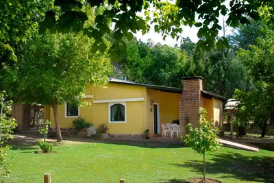 a yellow house with a lawn in front of it at La Olla Complejo Turistico in Santa Rosa de Calamuchita