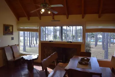 a dining room with a fireplace and tables and windows at La Olla Complejo Turistico in Santa Rosa de Calamuchita