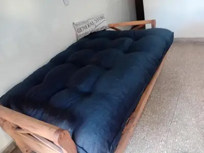 a bed with a blue blanket on a wooden frame at Alquimia Dos in Cordoba