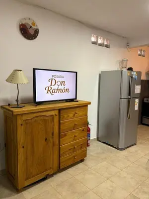 a television on top of a wooden cabinet next to a refrigerator at Posada Don Ramón in Estancia Vieja