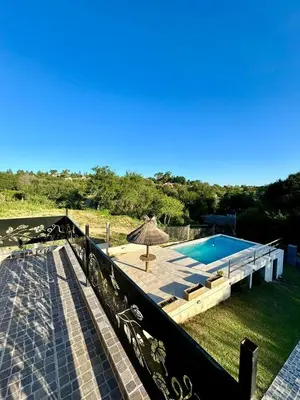 a house with a swimming pool and an umbrella at Jacarandá in Villa Carlos Paz