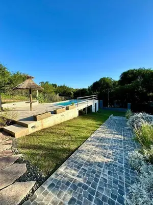 a walkway with an umbrella next to a pool at Jacarandá in Villa Carlos Paz