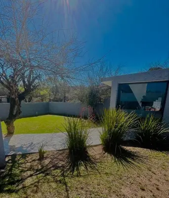 a house with a yard with plants in front of it at Jacarandá in Villa Carlos Paz