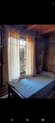 a bedroom with a bed with curtains and a window at Pao Pei in Santa Rosa de Calamuchita