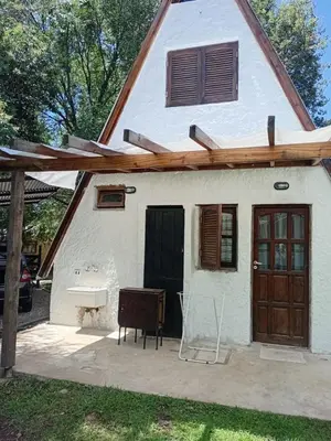 a small white house with a door and a bench at Alpinas El Chusmo 3 in Villa Ciudad Parque