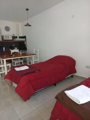a living room with a red bed and a table at Brisas del sol in Villa Carlos Paz