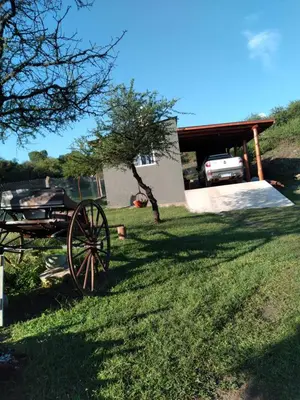 a wagon sitting in the grass in front of a house at Cabaña Don Americo in Villa García