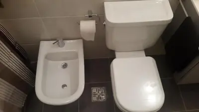 a bathroom with a toilet with a urinal next to it at Apartment Nueva Córdoba in Cordoba