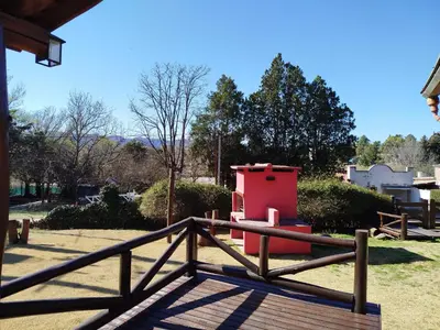 a wooden fence with a red object in a yard at Cabañas Fénix de Los Reartes in Los Reartes