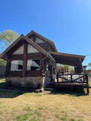 a log cabin with a large window and a porch at Cabañas Fénix de Los Reartes in Los Reartes