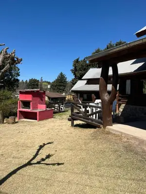a park with a wooden bench and a building at Cabañas Fénix de Los Reartes in Los Reartes