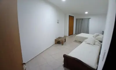 a white room with two beds and a table at Alojamiento ideal en zona norte de Córdoba Capital in Cordoba