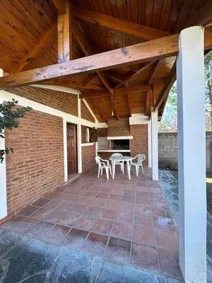 a patio with a wooden roof with a table and chairs at La Hormiga in Santa Rosa de Calamuchita