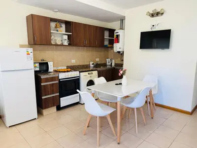 a kitchen with a white table and white appliances at Dpto céntrico VGB in Villa General Belgrano