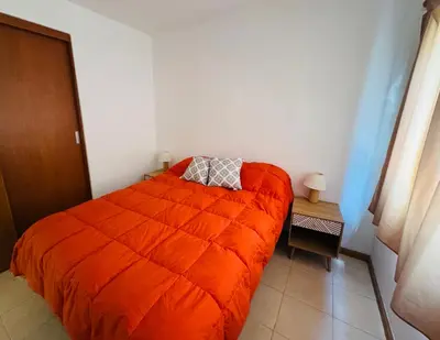 a bedroom with an orange comforter on a bed at Dpto céntrico VGB in Villa General Belgrano