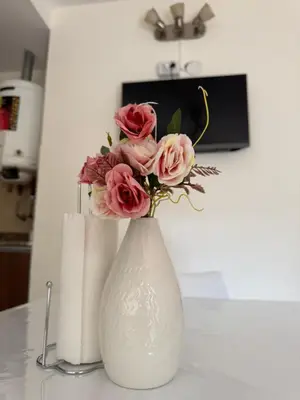 a white vase with pink roses in it on a table at Dpto céntrico VGB in Villa General Belgrano