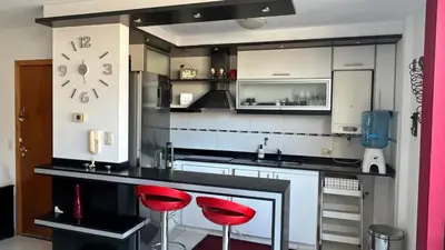 a kitchen with two red stools at a counter at Departamento Libertad in Villa Carlos Paz