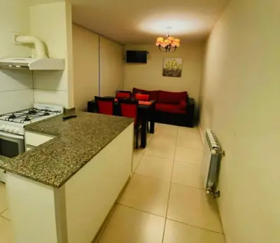 a kitchen and living room with a red couch in a room at Departamento Centrico Eutico in Villa Carlos Paz